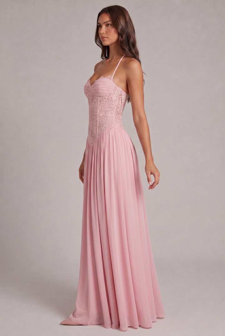 Vue de trois quarts de la robe rose portée, montrant la silhouette du corsage structuré et la jupe longue plissée. 3