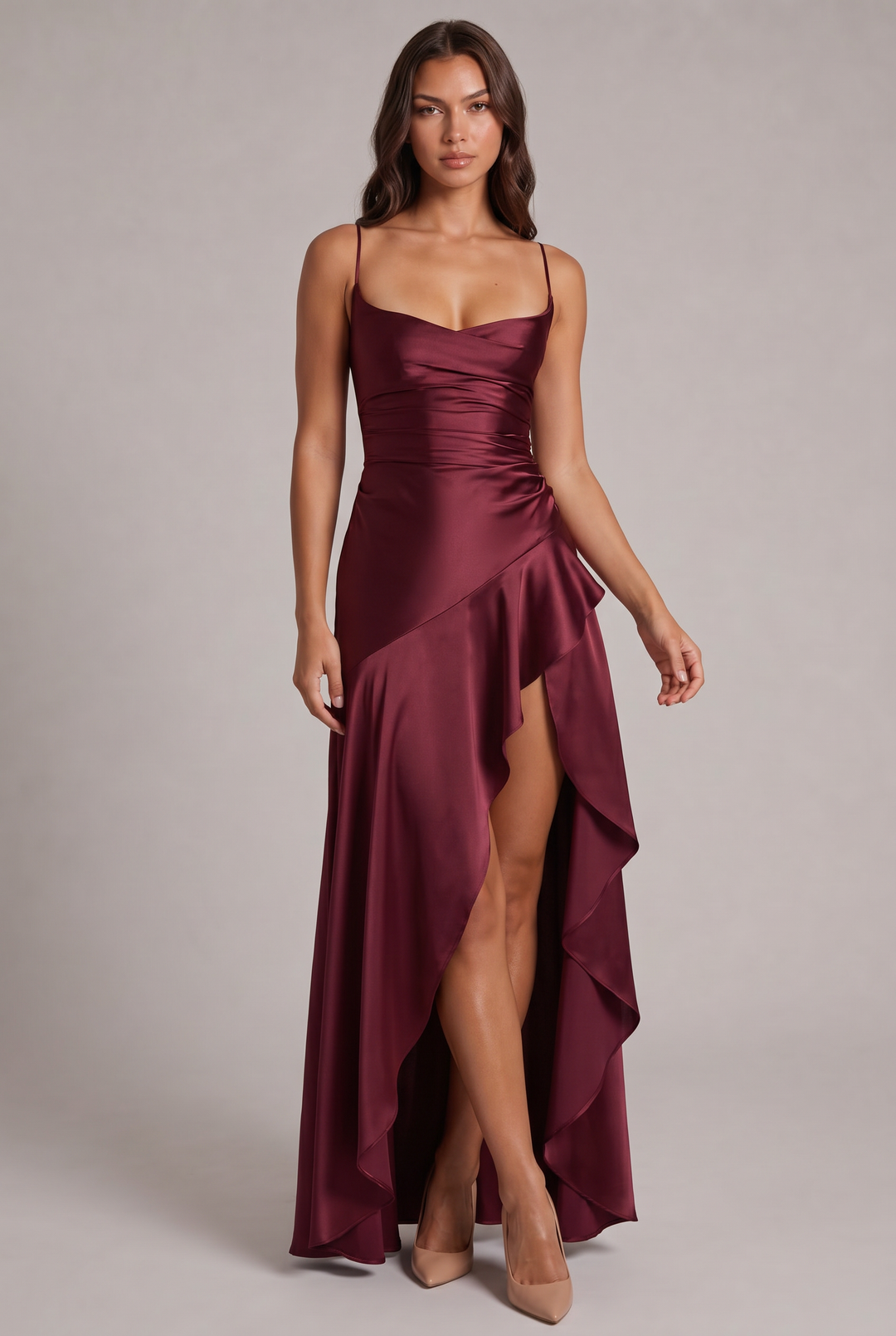 Robe longue bordeaux en satin portée de face par un mannequin, avec fines bretelles, taille drapée et haute fente volantée. 1