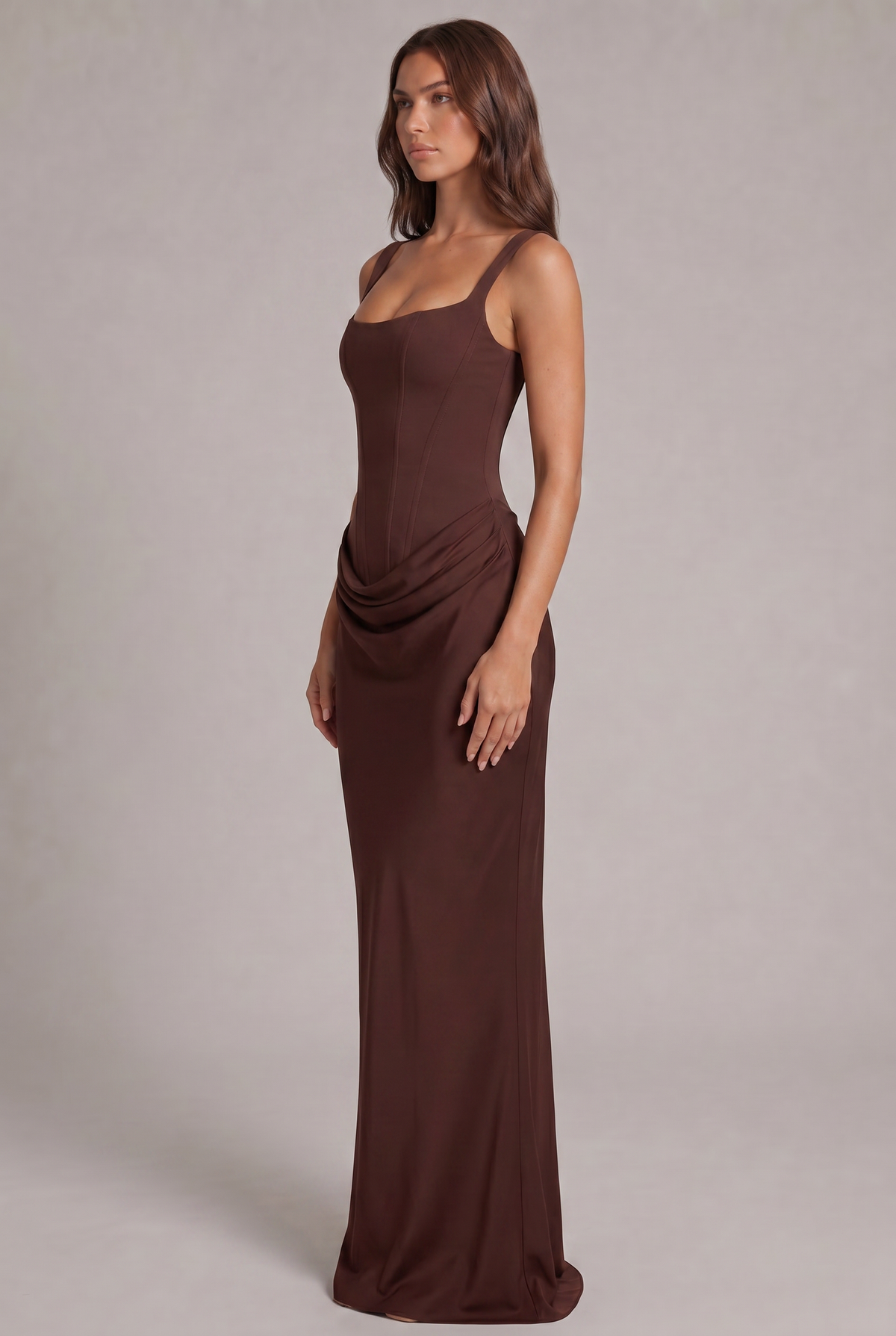 Robe longue marron vue de trois quarts, silhouette près du corps avec corsage structuré et drapé sur la hanche. 3