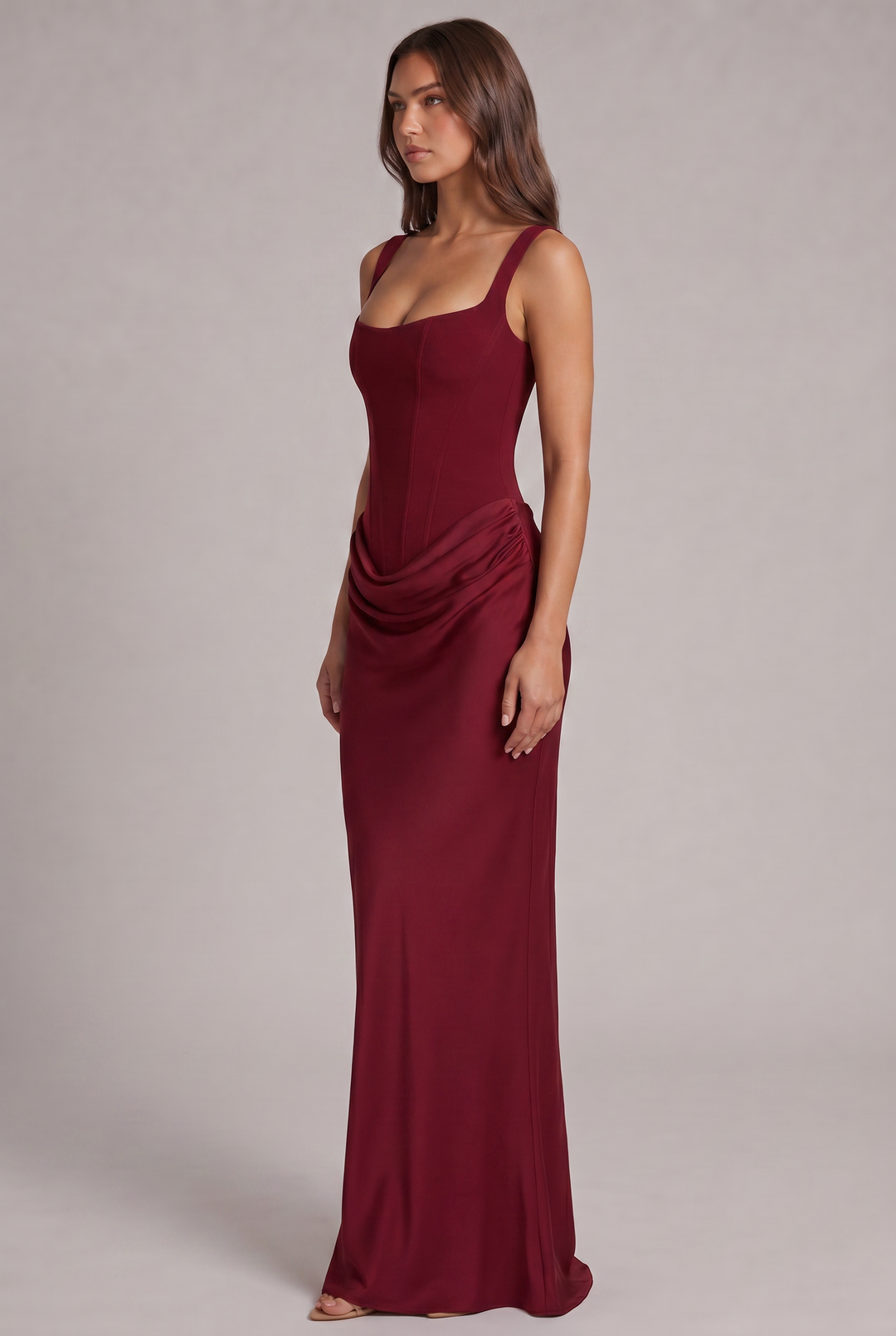 Robe bordeaux vue de trois quarts, silhouette cintrée avec drapé sur la hanche et jupe longue fluide. 19