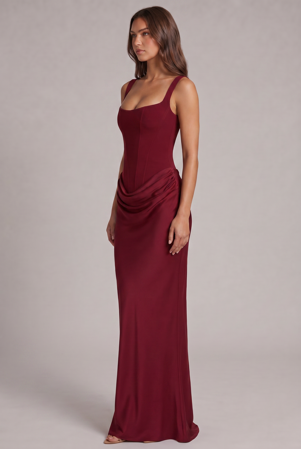 Robe bordeaux vue de trois quarts, silhouette cintrée avec drapé sur la hanche et jupe longue fluide. 19