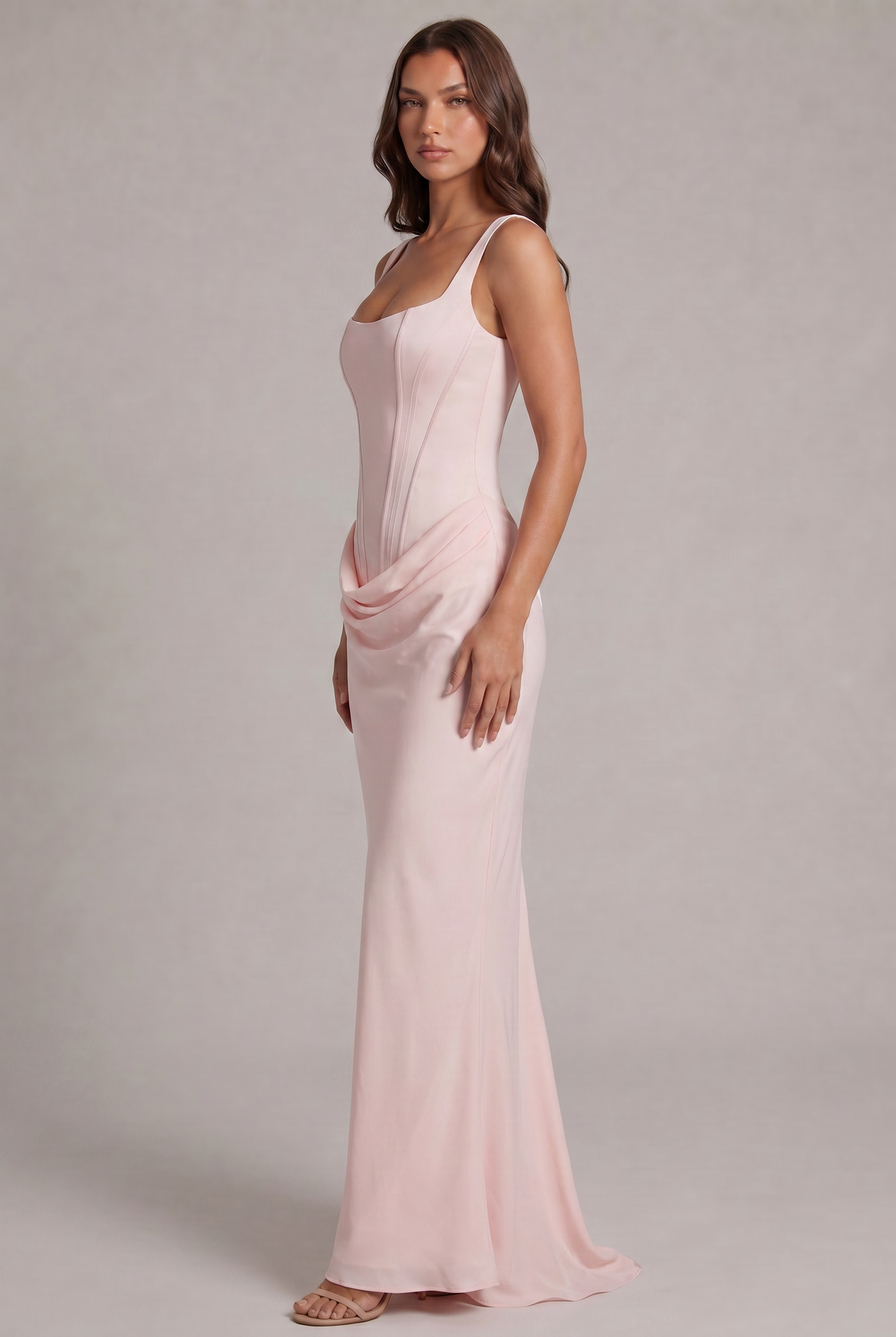Robe rose pâle vue de trois quarts, corsage ajusté, drapé sur la hanche et jupe longue fluide avec petite traîne. 27