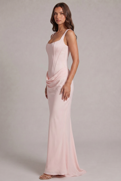 Robe rose pâle vue de trois quarts, corsage ajusté, drapé sur la hanche et jupe longue fluide avec petite traîne. 27