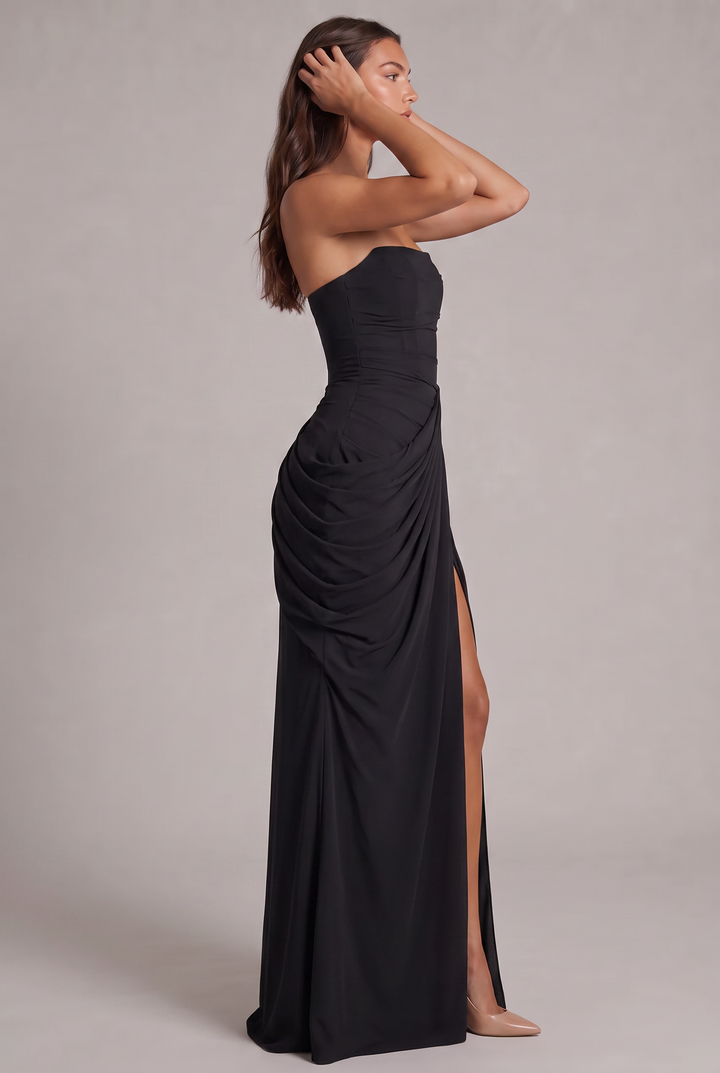 Robe noire vue de profil, mannequin les mains dans les cheveux, drapé volumineux sur la hanche 27