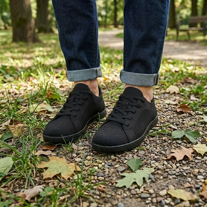 Pieds portant les baskets noires sur un sentier de graviers et de feuilles, avec un jean retroussé. 11