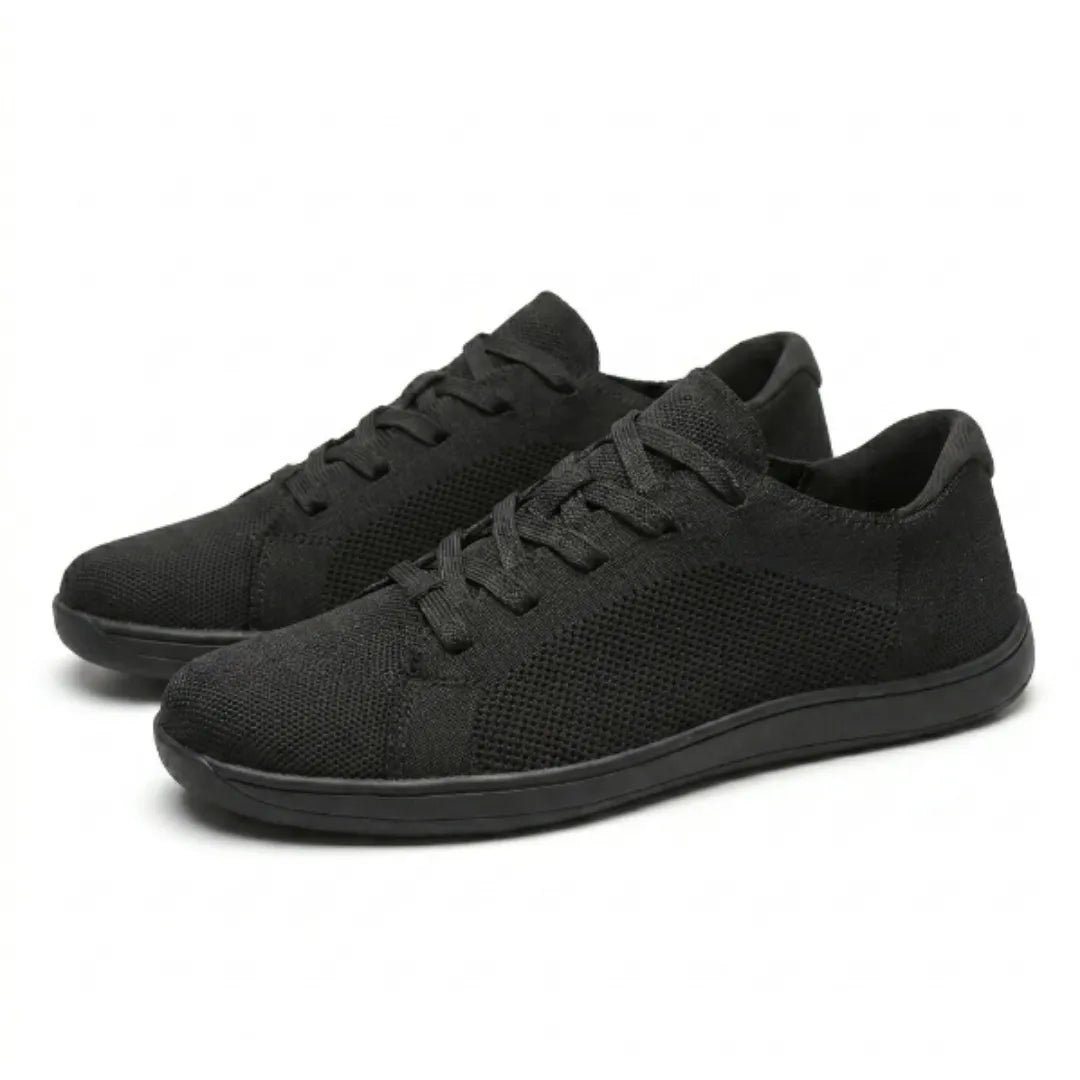 Paire de baskets noires en maille vue en trois quarts, lacets plats et semelle fine noire. 16