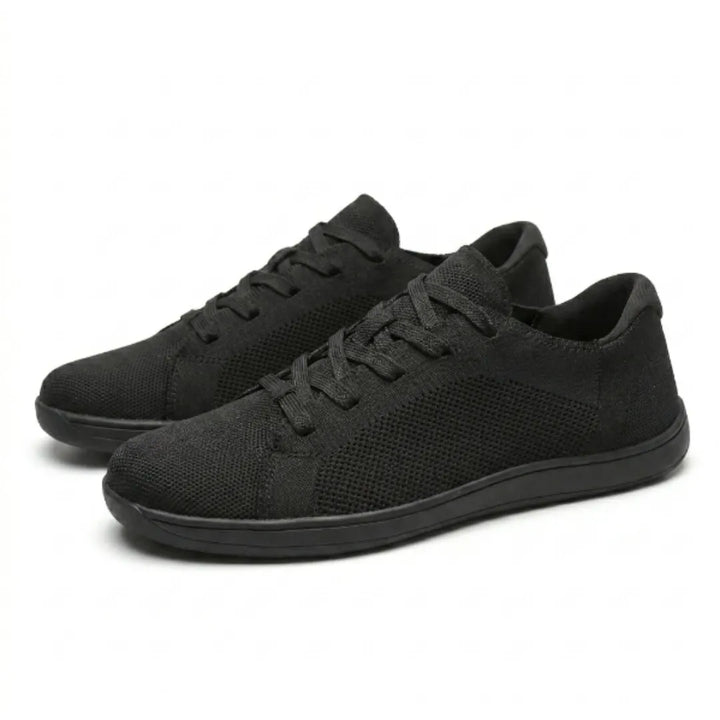 Paire de baskets noires en maille vue en trois quarts, lacets plats et semelle fine noire. 16