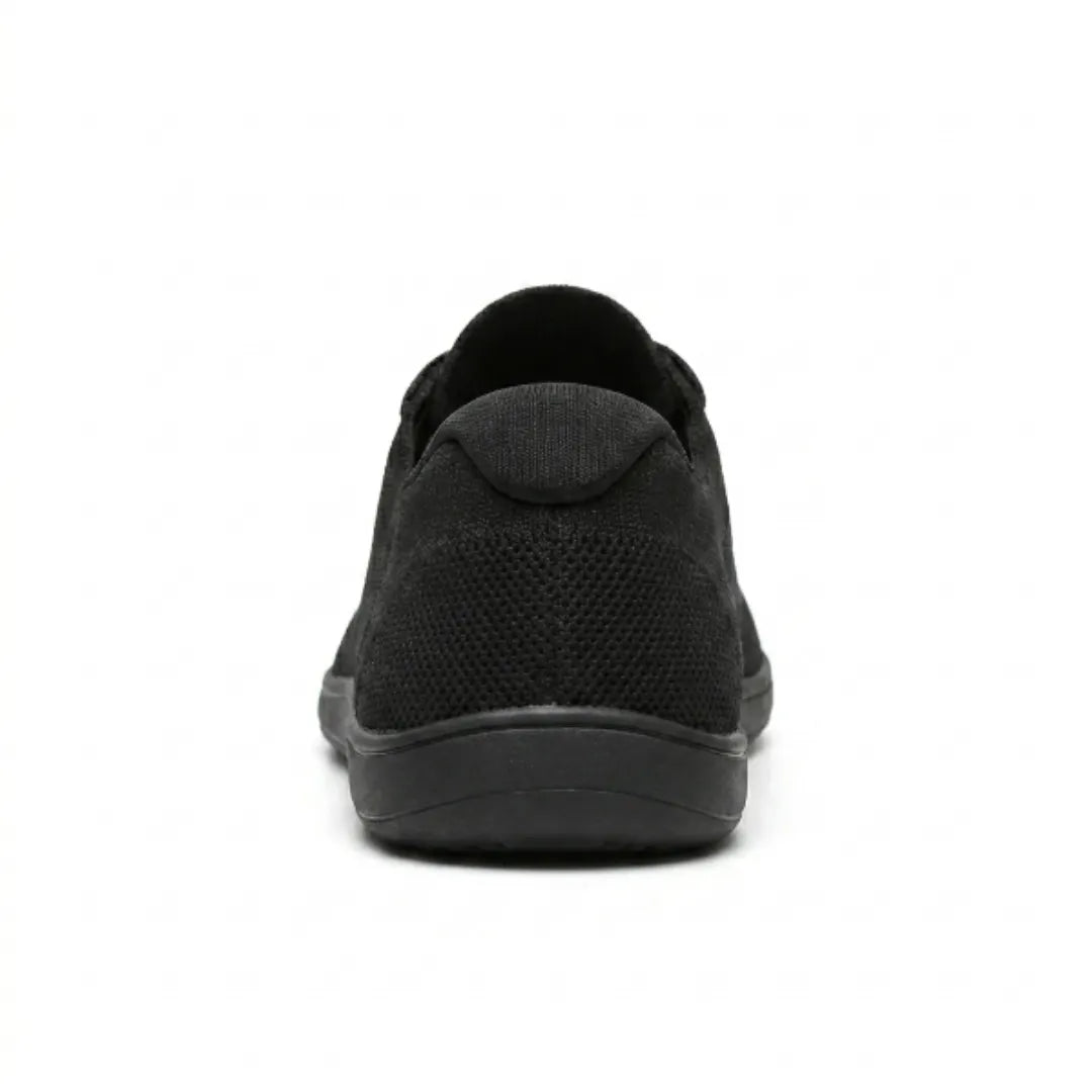 Vue arrière de la basket noire, montrant le contrefort du talon en maille et la semelle plate. 18
