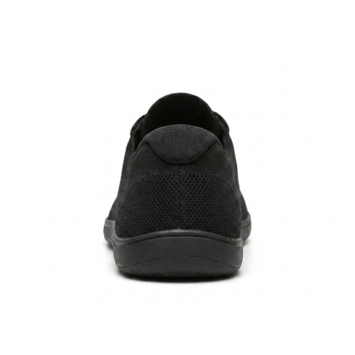 Vue arrière de la basket noire, montrant le contrefort du talon en maille et la semelle plate. 18