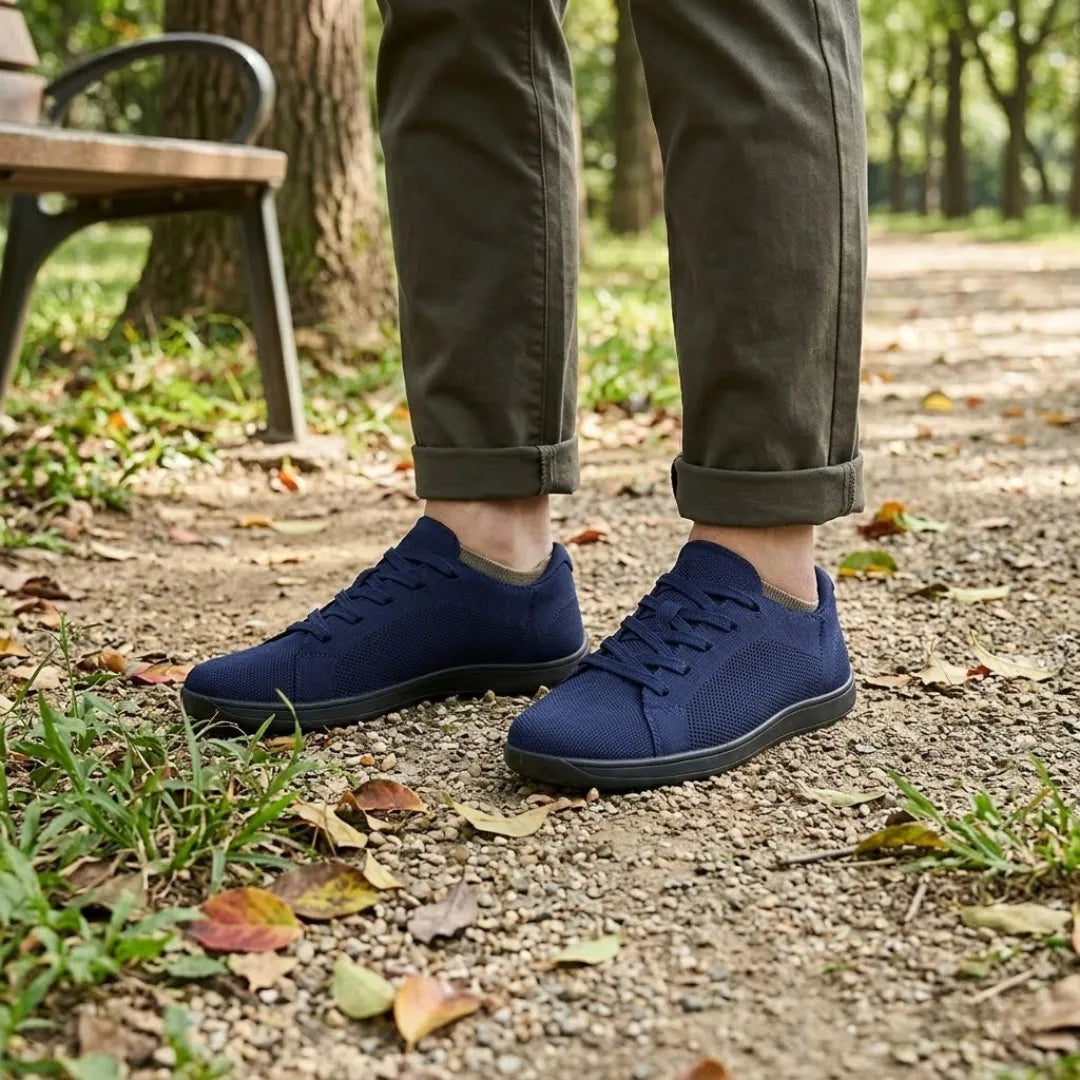 Pieds portant les baskets bleu marine à semelle noire sur un chemin de parc, avec un pantalon kaki foncé retroussé. 20