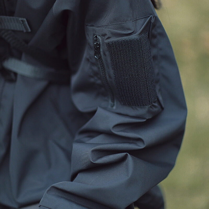 Détail de la manche de la veste noire avec poche zippée et bande de fermeture à scratch. 6