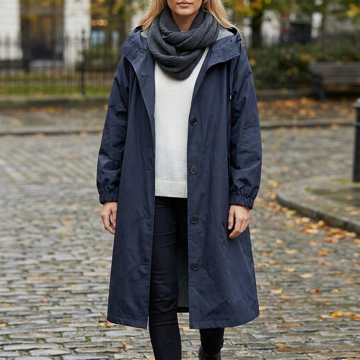 Imperméable long bleu marine vu de face, porté en ville sur des pavés couverts de feuilles d'automne. 7