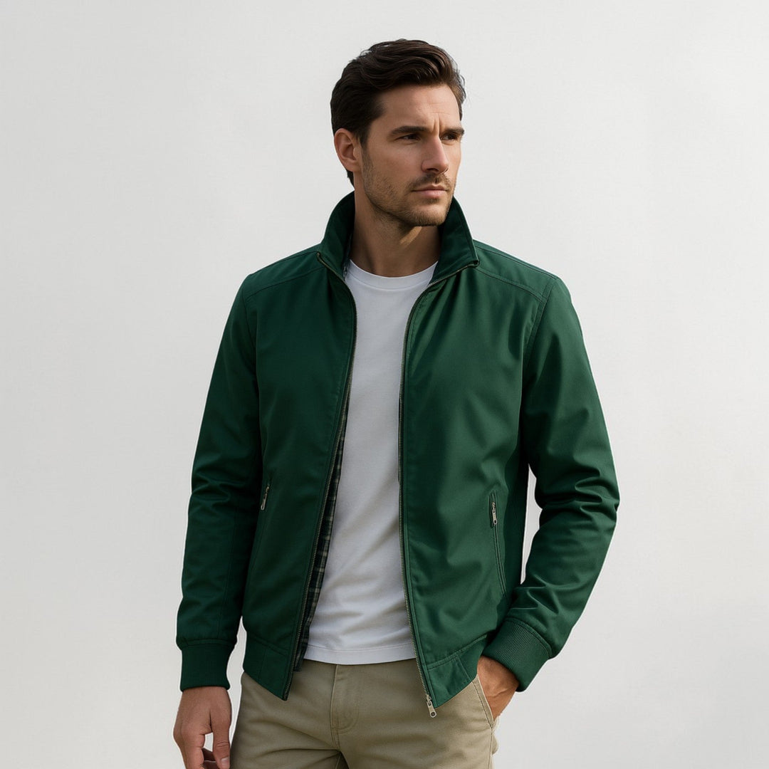 Homme portant la veste verte ouverte sur un t-shirt blanc, doublure à carreaux visible, pantalon beige et main dans la poche. 3