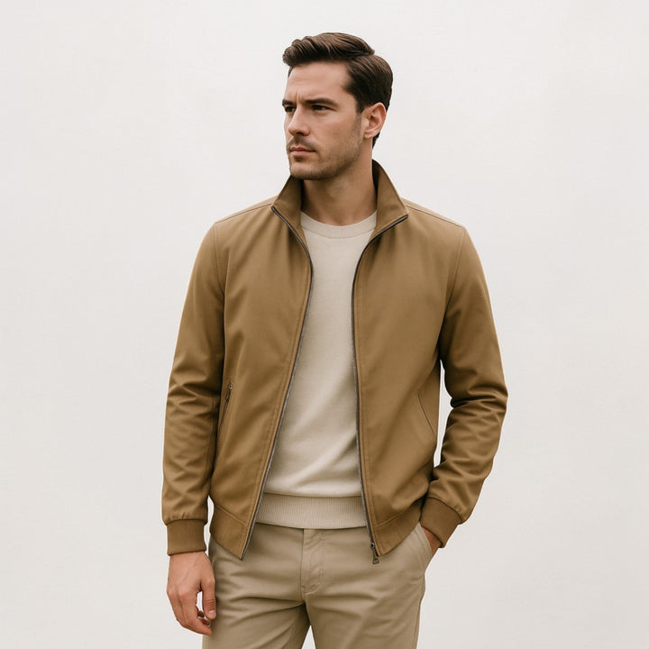 Homme portant la veste couleur camel ouverte sur un pull crème, avec un pantalon beige et une main dans la poche. 4