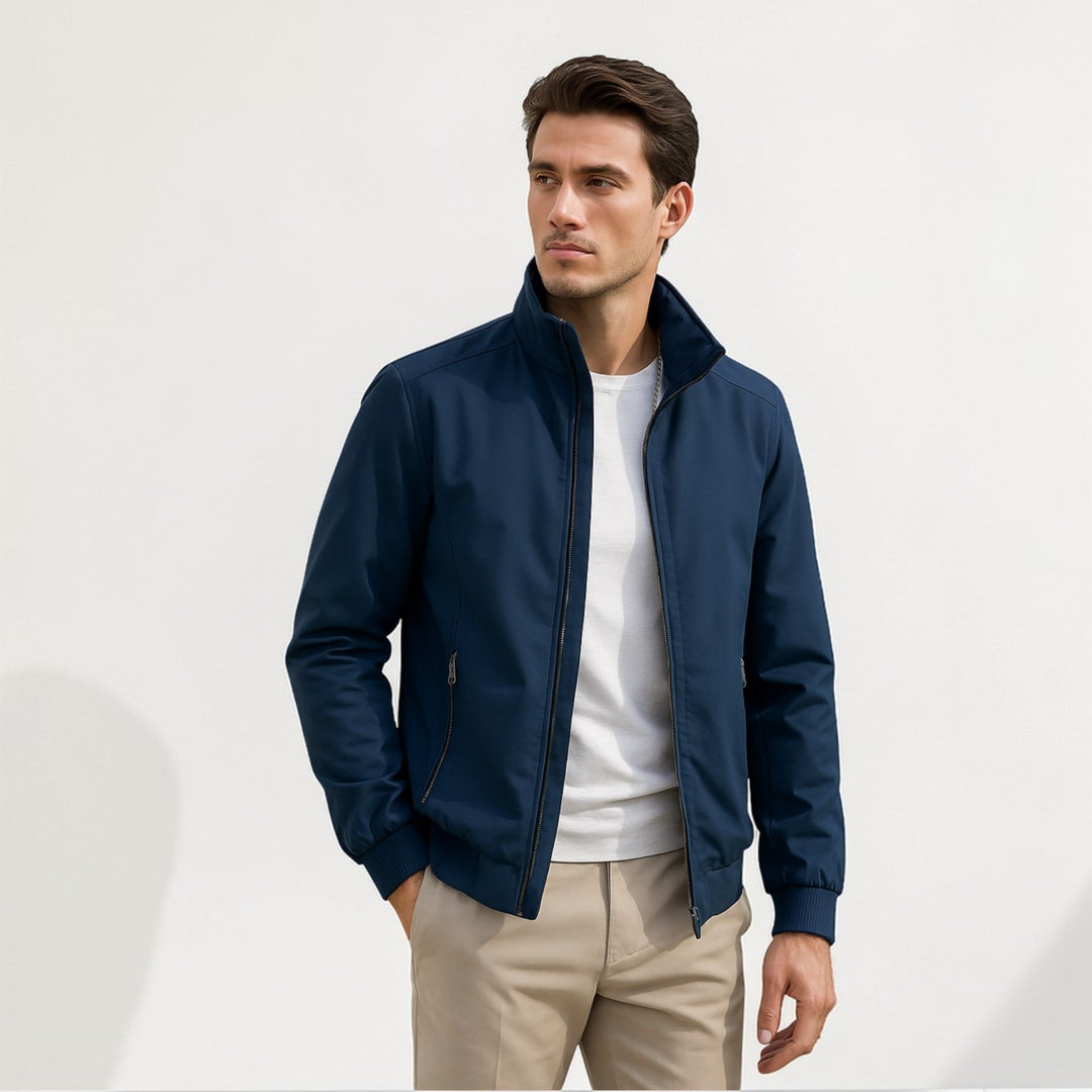 Homme portant la veste bleu marine ouverte sur un t-shirt blanc, avec un pantalon beige, col montant et poches zippées. 1