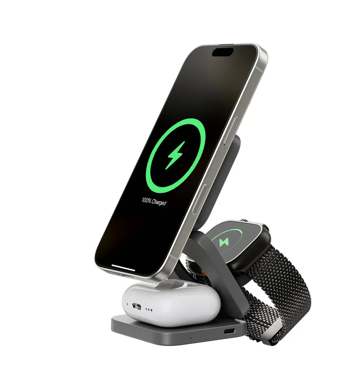 Version gris foncé de la station dépliée, chargeant un smartphone à cadre clair, une montre à bracelet maille et un boîtier d'écouteurs. 3