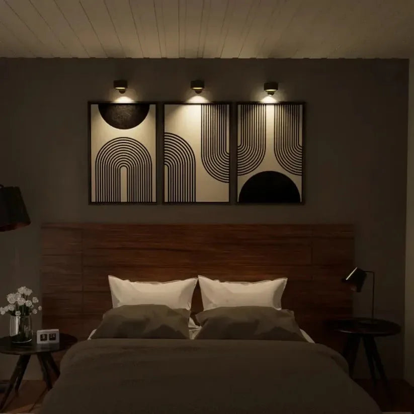 Trois lampes murales noires allumées éclairant trois tableaux graphiques au-dessus d'un lit dans une chambre sombre 10