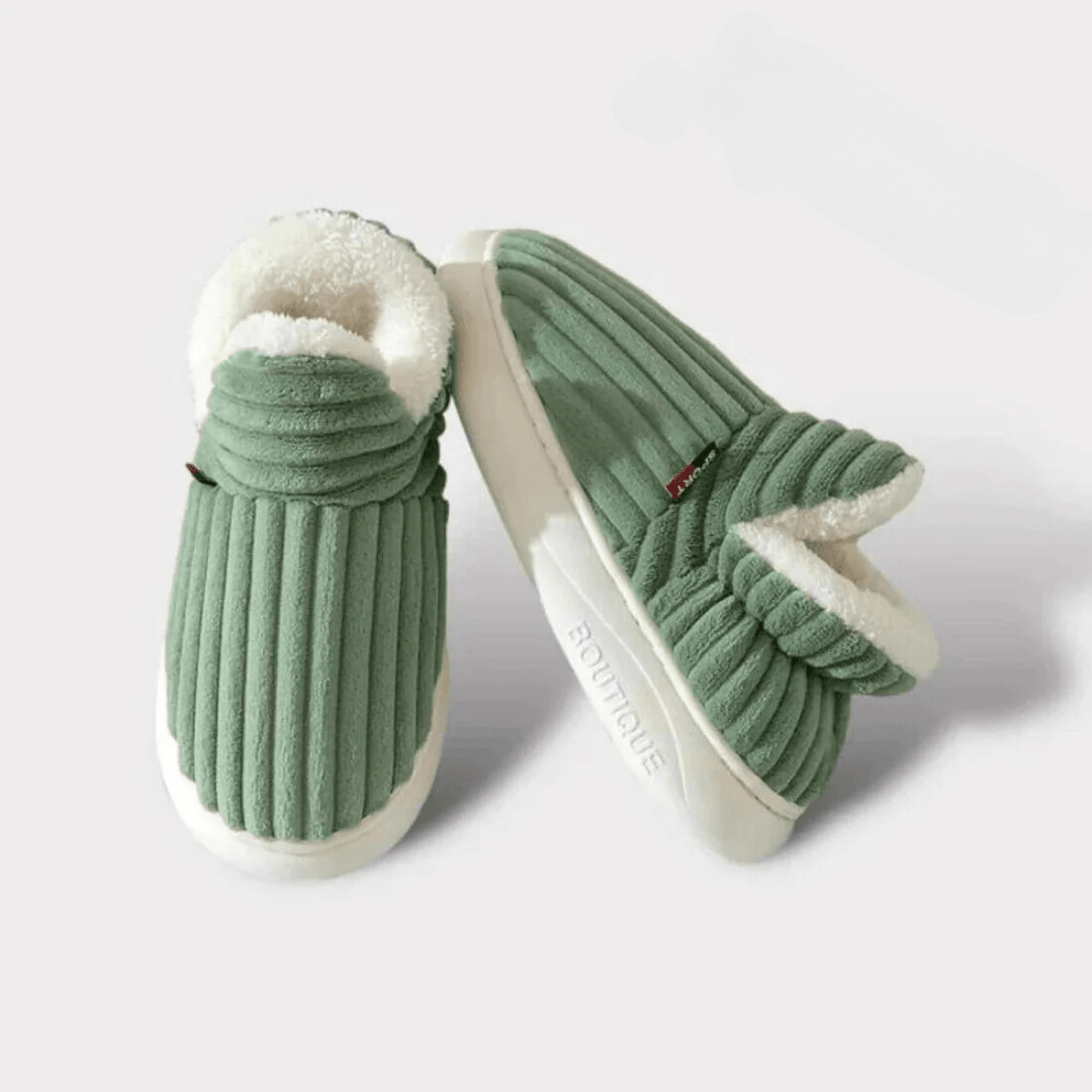Paire de chaussons verts côtelés sur fond clair, l'un posé de face, l'autre de côté montrant la semelle épaisse. 16