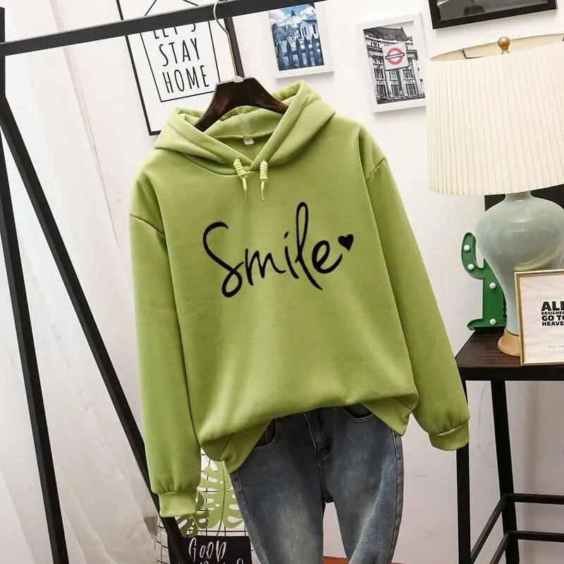 Sweat à capuche vert pomme présenté sur cintre, cordons à la capuche, motif noir manuscrit avec petit cœur, assorti à un jean. 5