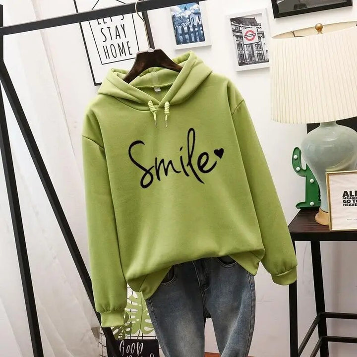 Sweat à capuche vert pomme présenté sur cintre, cordons à la capuche, motif noir manuscrit avec petit cœur, assorti à un jean. 5