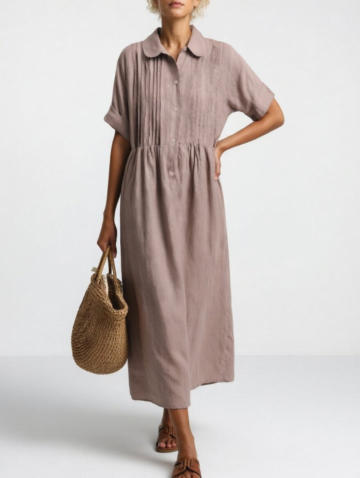 Robe taupe rosé portée par une femme, main sur la hanche, panier en paille à la main, vue de face. 8