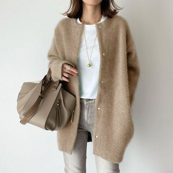 Gilet duveteux beige à boutons-pression porté sur un t-shirt blanc, avec un sac beige à la main 1