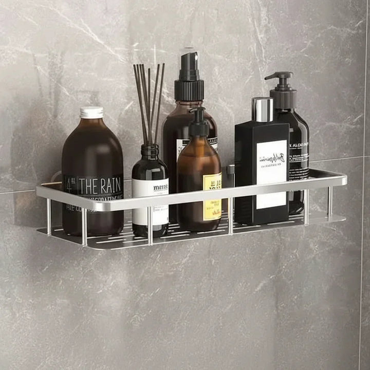 Étagère argentée au fond ajouré, remplie de flacons ambrés et noirs, sur un mur en marbre gris 5