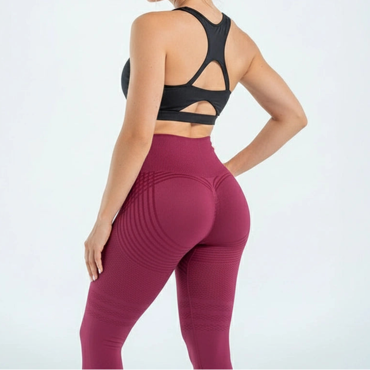 Femme de dos en leggings bordeaux taille haute, avec rayures courbes sur les fesses et couture galbante, brassière noire échancrée. 6