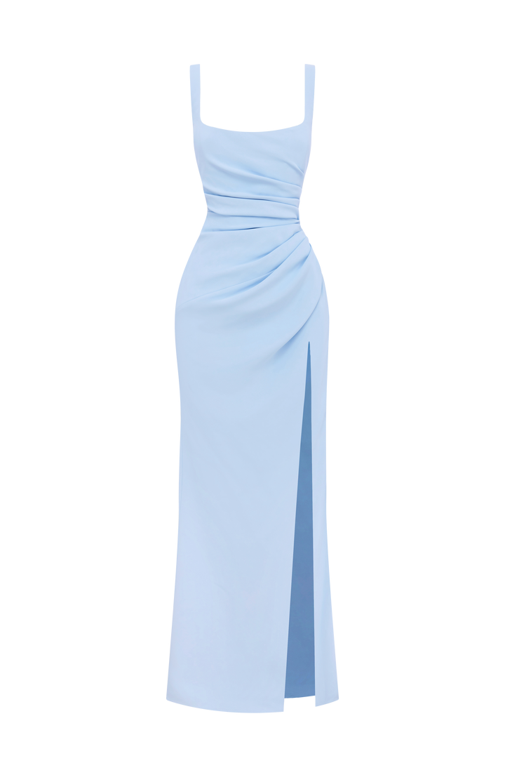 Robe bleu ciel présentée à plat sur fond blanc, vue de face, avec drapé à la taille et fente latérale doublée. 29