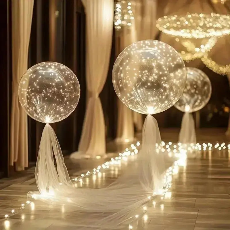 Ballons transparents éclairés, noués de tulle blanc et posés sur un sol brillant, bordé d'une guirlande lumineuse. 6