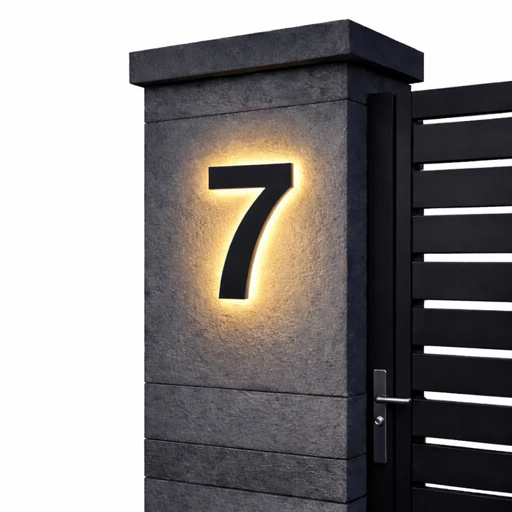 Chiffre 7 noir à halo lumineux chaud, monté sur un pilier en pierre sombre près d'un portail à lames, fond blanc. 5