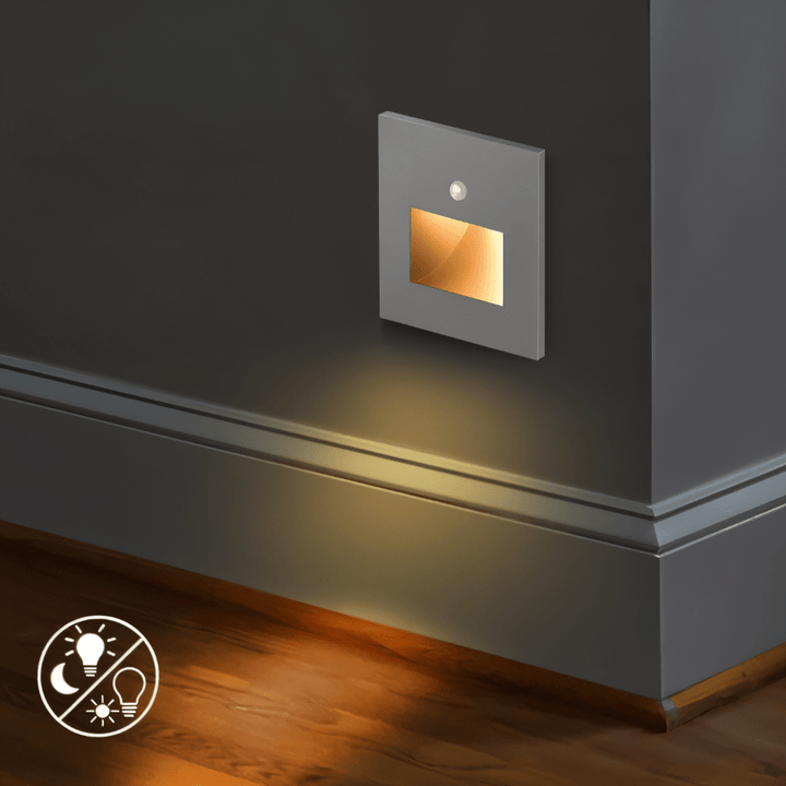 Applique grise allumée en bas d'un mur, diffusant une lumière chaude sur la plinthe et le parquet 5
