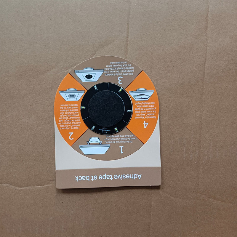 Carte guide d'installation orange et beige en quatre étapes, posée sur du carton, avec un autocollant d'alignement noir au centre. 11