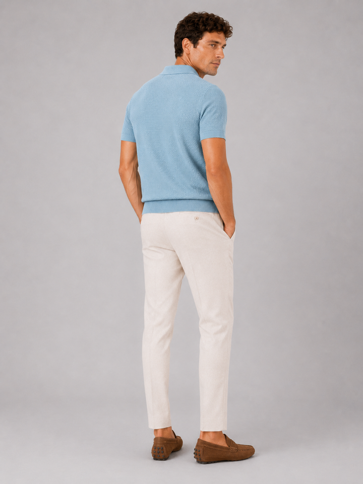 Polo bleu clair vu de dos sur un homme tourné de côté, pantalon beige et mocassins 4