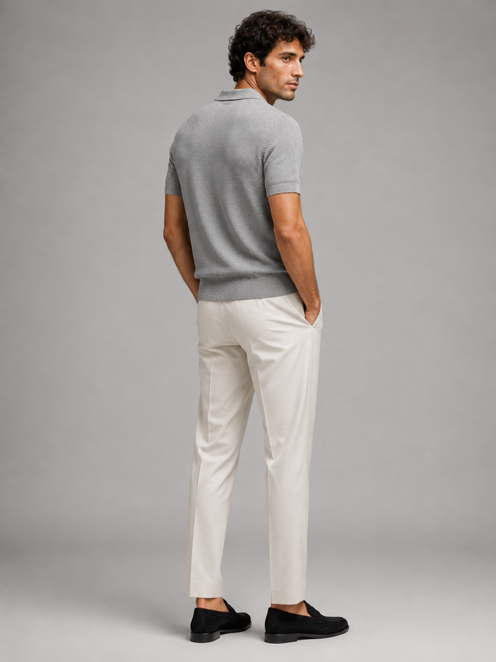 Vue de dos du polo gris porté avec pantalon écru, mains dans les poches 29