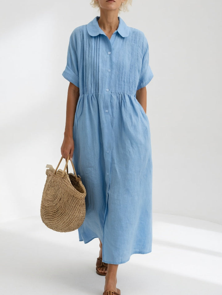 Robe bleu ciel vue de face sur une femme, avec col rond, boutons sur le devant et plis sur la poitrine. 2