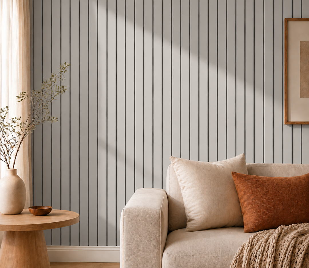 Gros plan sur un mur de lattes grises et rainures sombres, avec canapé beige et coussin rouille 16