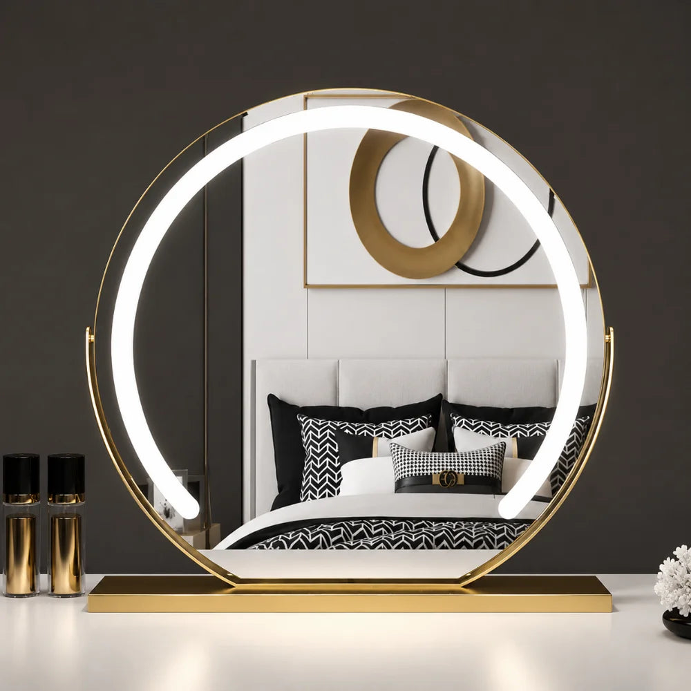 Miroir rond doré allumé sur une coiffeuse blanche, avec deux flacons dorés à côté 10