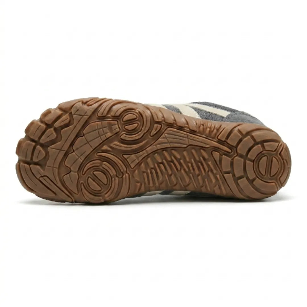 Dessous de la chaussure grise montrant la semelle caramel aux motifs de crampons et de rainures variés. 9