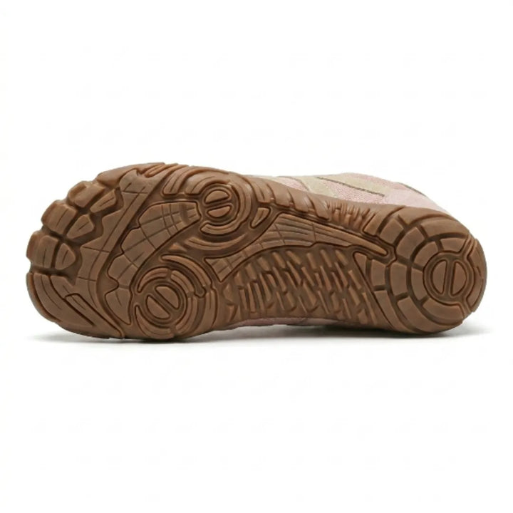 Dessous de la chaussure rose montrant la semelle caramel aux motifs de crampons et de rainures variés. 18