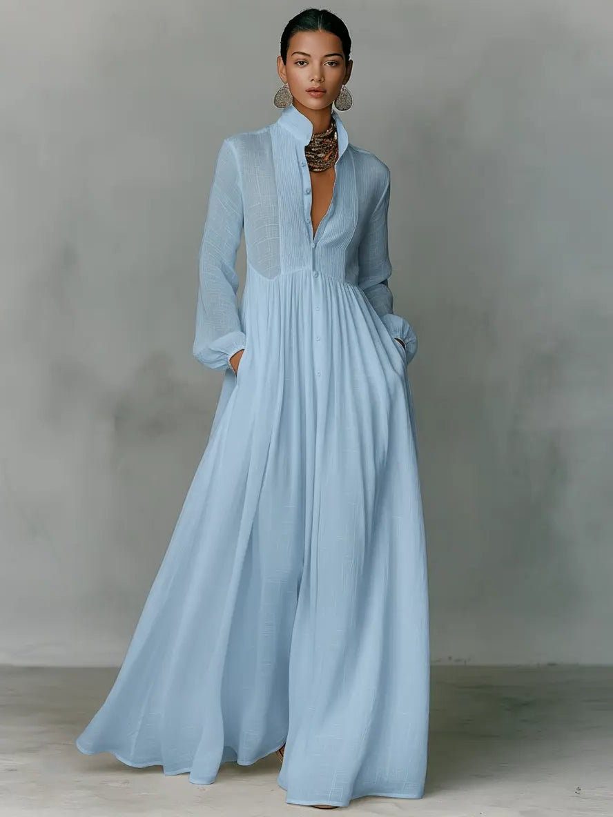 Robe maxi bleu ciel portée de face avec collier et boucles d'oreilles, mains dans les poches 3