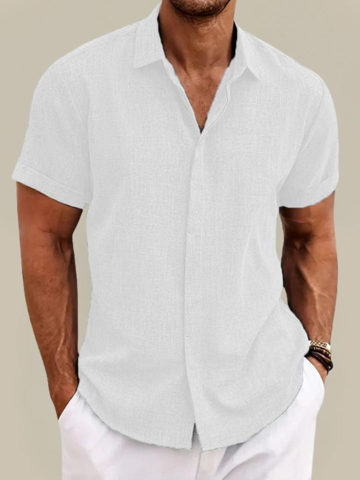 Version blanche de la chemise à manches courtes, portée par un homme avec un pantalon blanc et des bracelets au poignet. 4