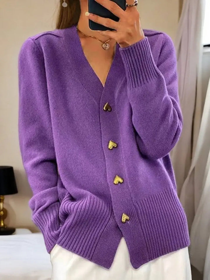 Version violette portée avec un pantalon blanc, laissant voir les boutons cœur dorés et les poignets côtelés. 3