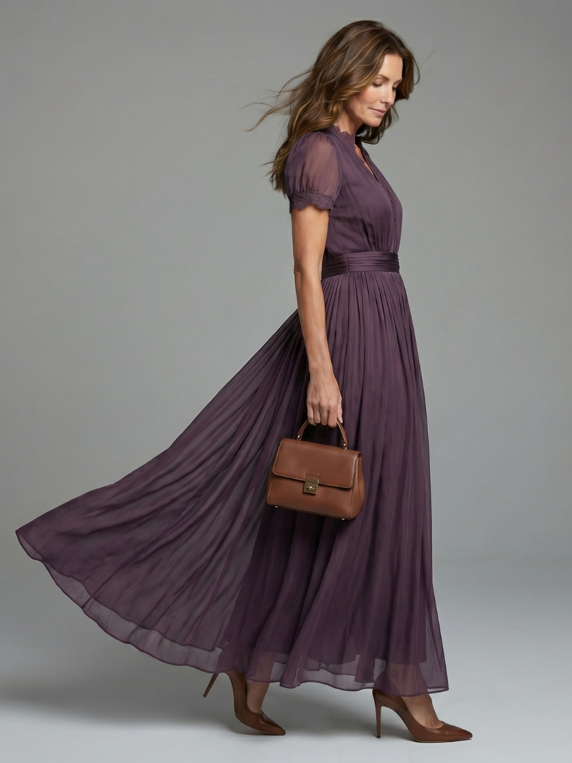 Vue de profil de la robe prune en mousseline qui flotte au mouvement, avec ceinture plissée à la taille et escarpins marron. 2