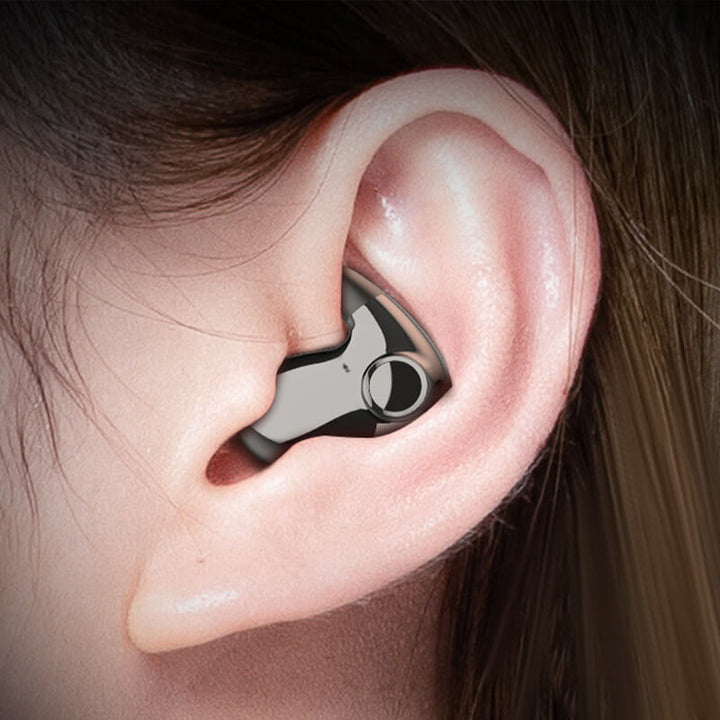 Gros plan d'une oreille portant un écouteur gris métallisé discret avec un bouton rond 1