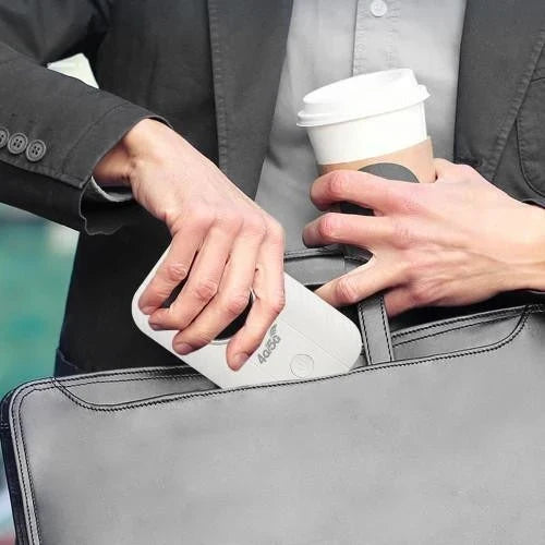 Un homme glisse le petit boîtier blanc dans sa sacoche, un gobelet de café à la main 2