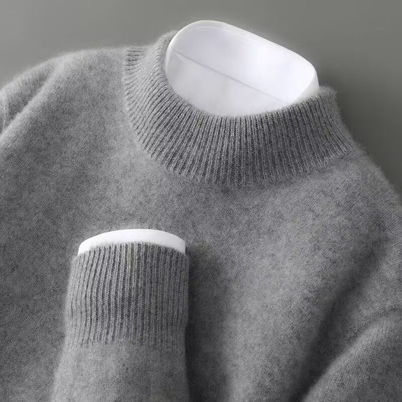 Pull gris chiné à col rond côtelé vu de près, avec une chemise blanche qui dépasse du col et du poignet. 5