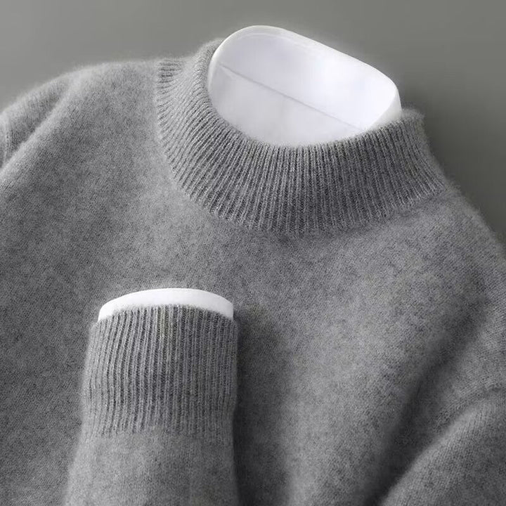 Pull gris chiné à col rond côtelé vu de près, avec une chemise blanche qui dépasse du col et du poignet. 5