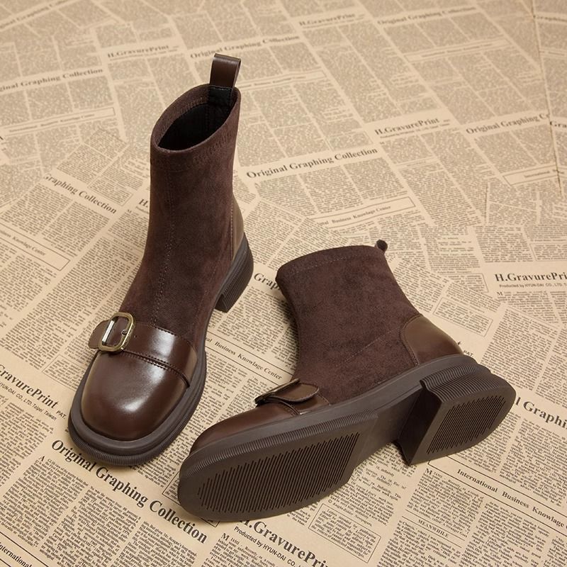 Paire de bottines marron en daim et cuir lisse, l'une debout avec boucle dorée, l'autre couchée montrant la semelle crantée. 1