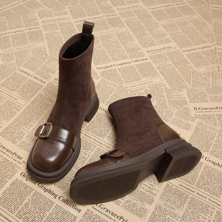 Paire de bottines marron en daim et cuir lisse, l'une debout avec boucle dorée, l'autre couchée montrant la semelle crantée. 1